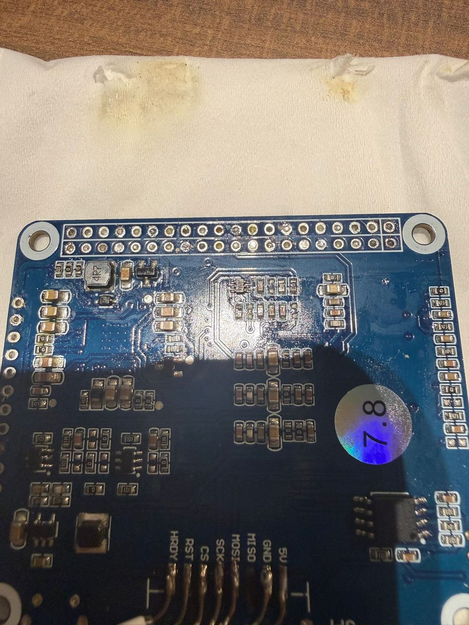 A driver board taped and hot-glued into a piece of white packing foam, with wires hand-soldered directly to the board's SPI pads.