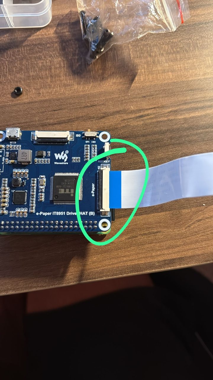 The driver board with the display ribbon connector circled in green marker, the ribbon partially inserted.